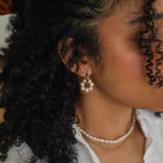 Kullatut helmikorvakorut naisen päällä