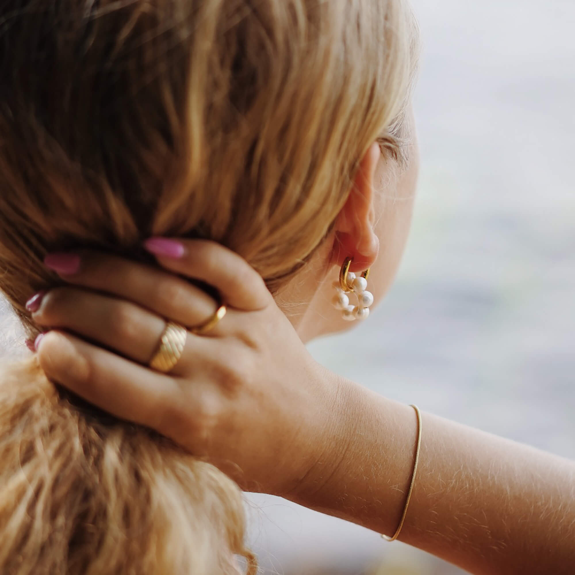 Kullatut aqua circle helmikorvakorut naisen päällä