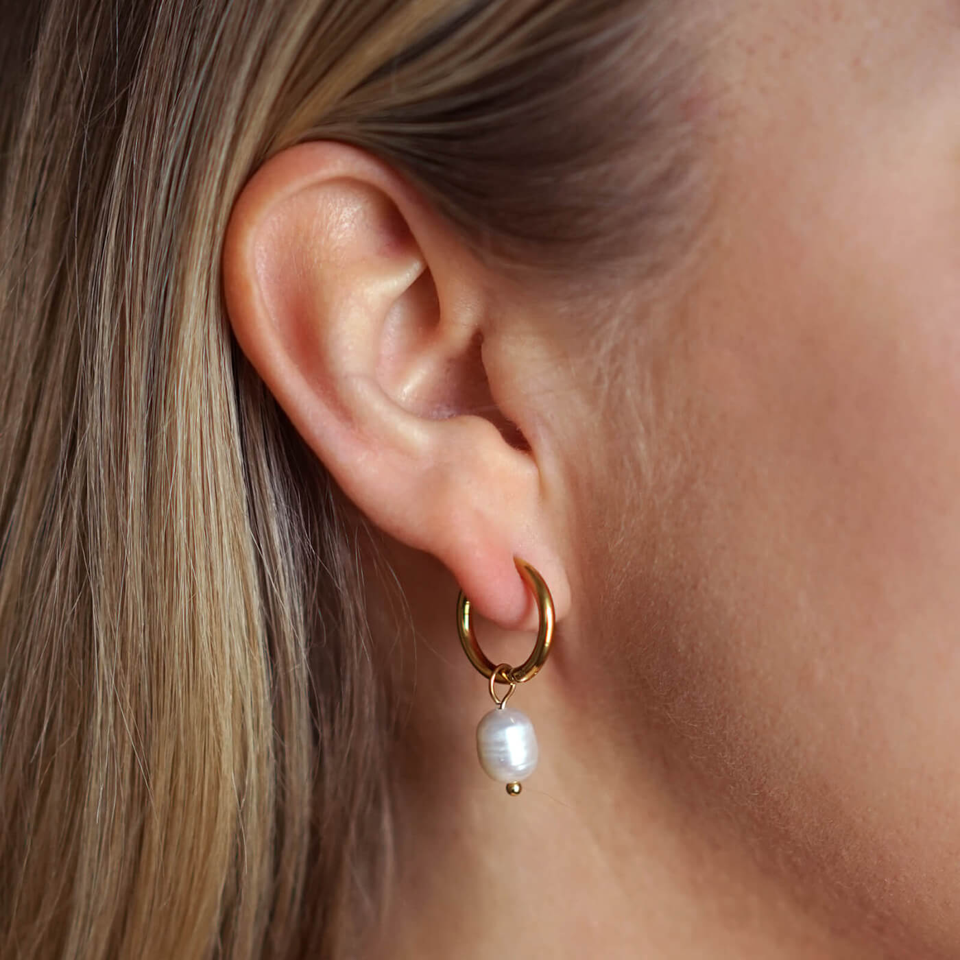 Makeanvedenhelmikorvakorut naisen yllä