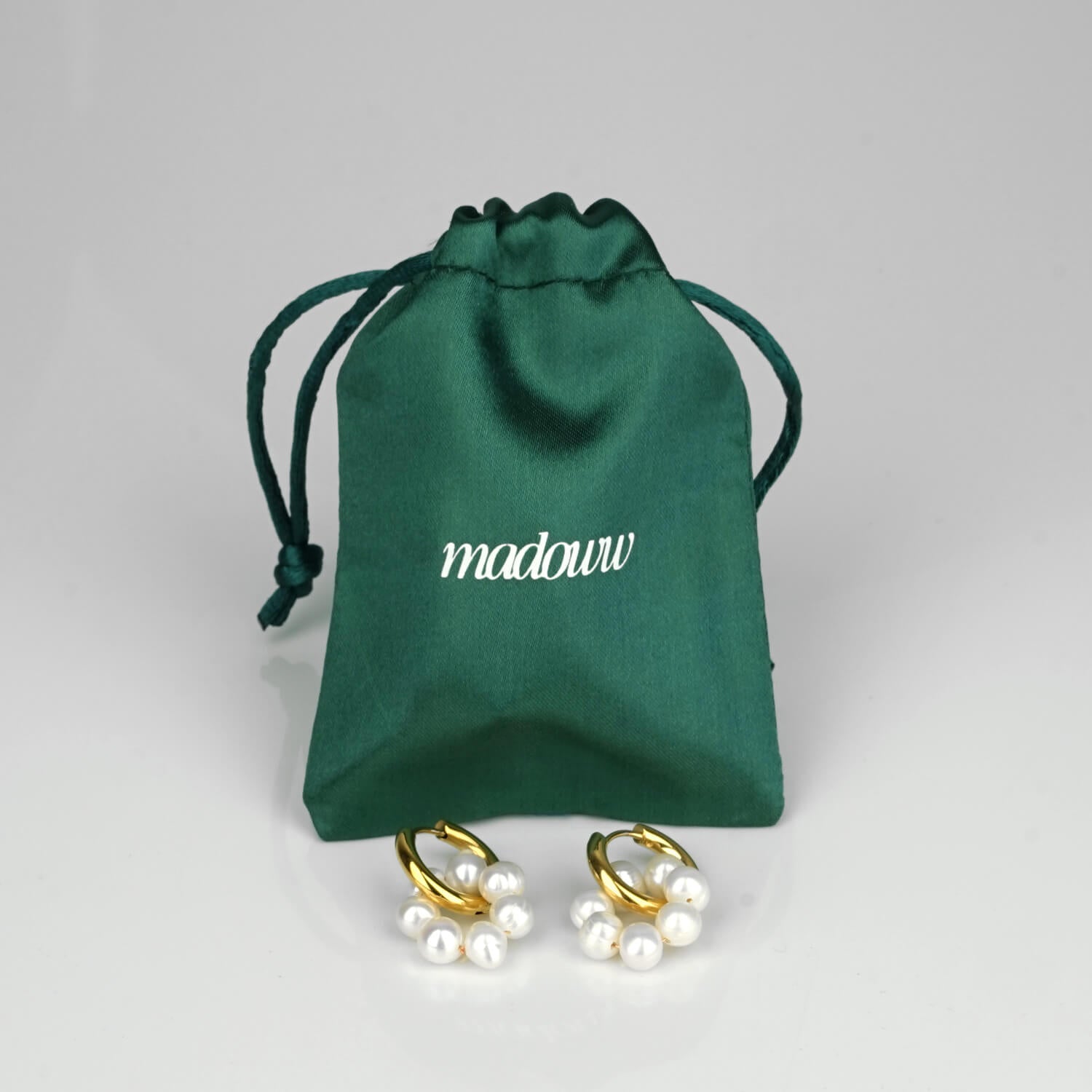 Aqua circle kullatut helmikorvakorut satiinipussin edessä