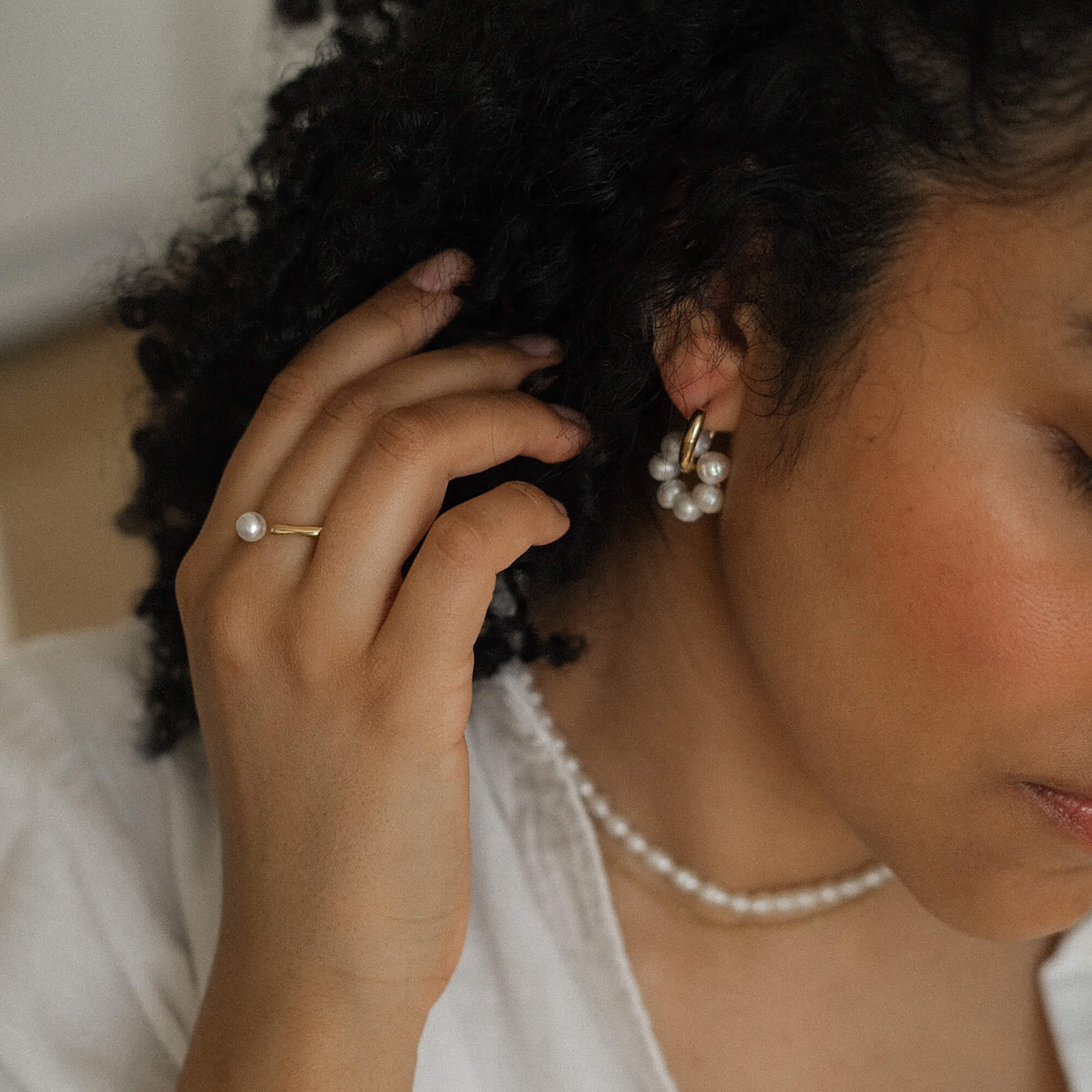 Säädettävä sormus jossa koristeena helmi naisen sormessa