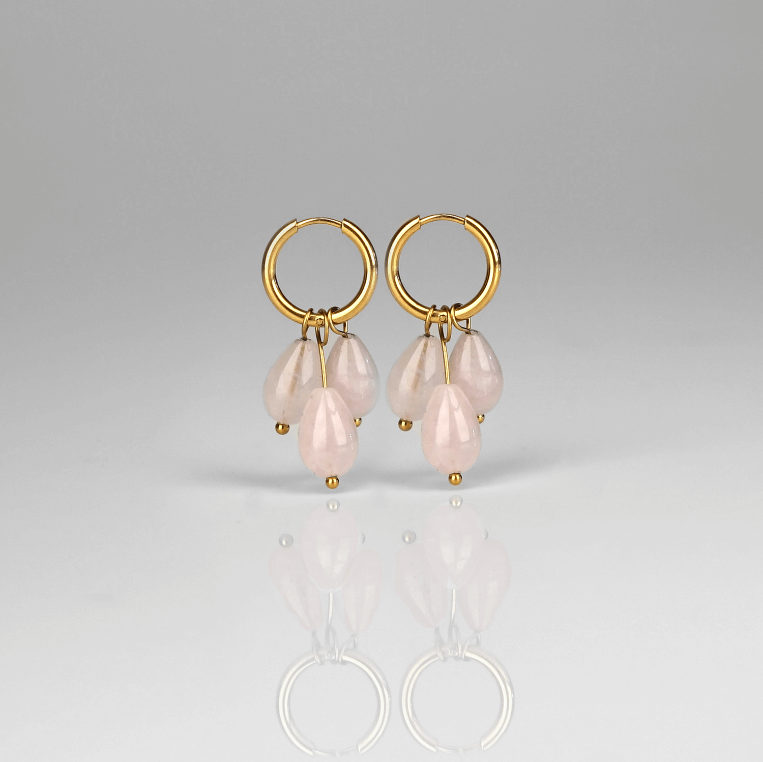Madowwn Cascade Blossom kullatusta ruostumattomasta teräksestä valmistetut korvakorut roikkuvilla vaaleanpunaisilla luonnonkivillä valkoista taustaa vasten