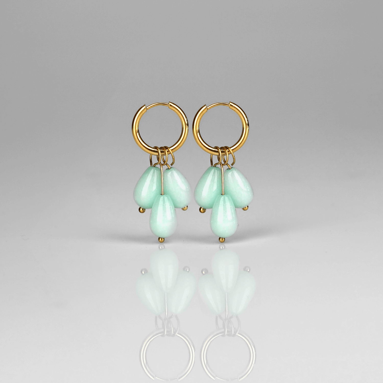 Madowwn Cascade Mist kullatusta ruostumattomasta teräksestä valmistetut korvakorut roikkuvilla sinertävillä luonnonkivillä valkoista taustaa vasten