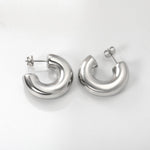 Hopeat ruostumattomasta teräksestä valmistetut hypoallergiset korvakorut valkoisella taustalla