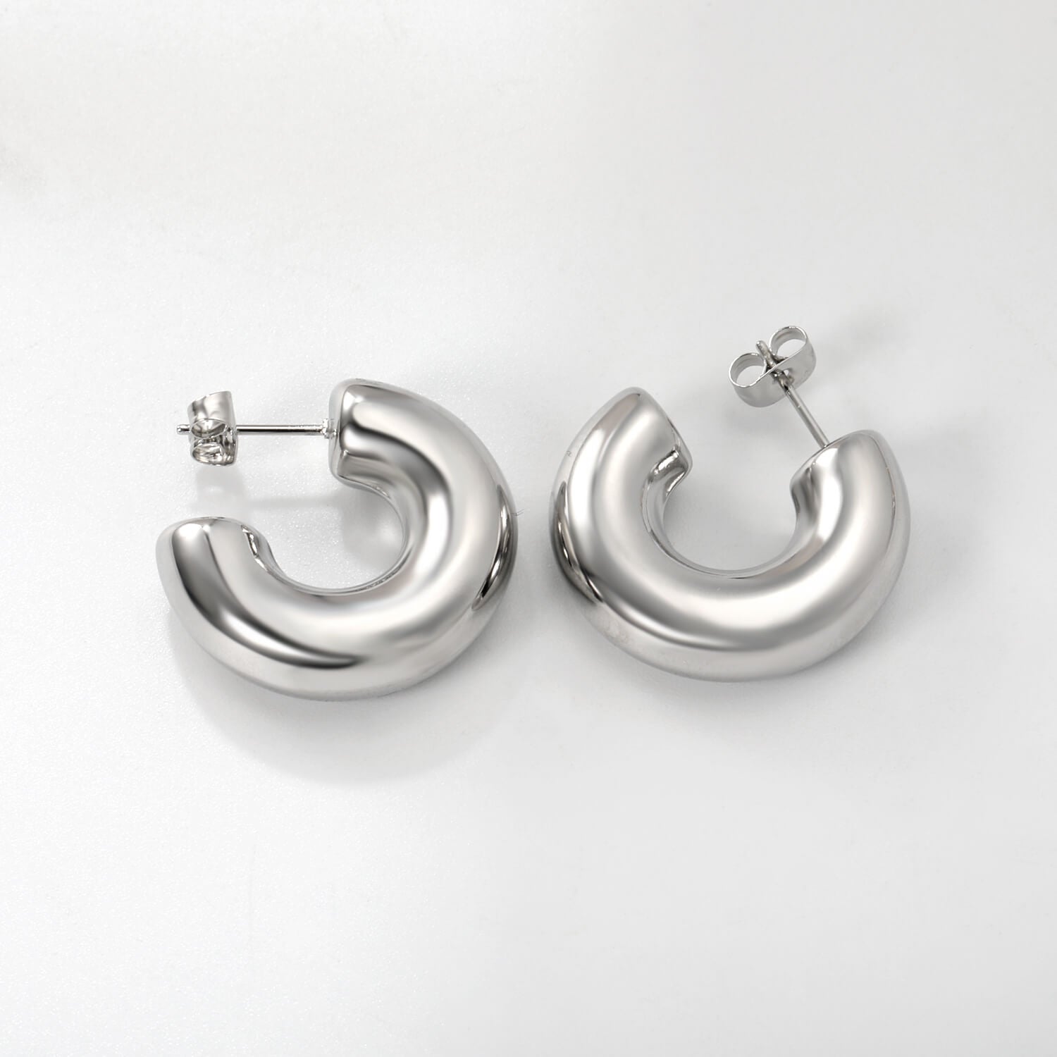 Hopeat ruostumattomasta teräksestä valmistetut hypoallergiset korvakorut valkoisella taustalla