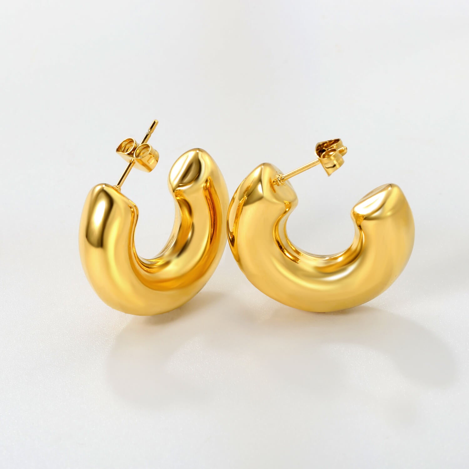 Kullatut chunky korvakorut valkoisella taustalla