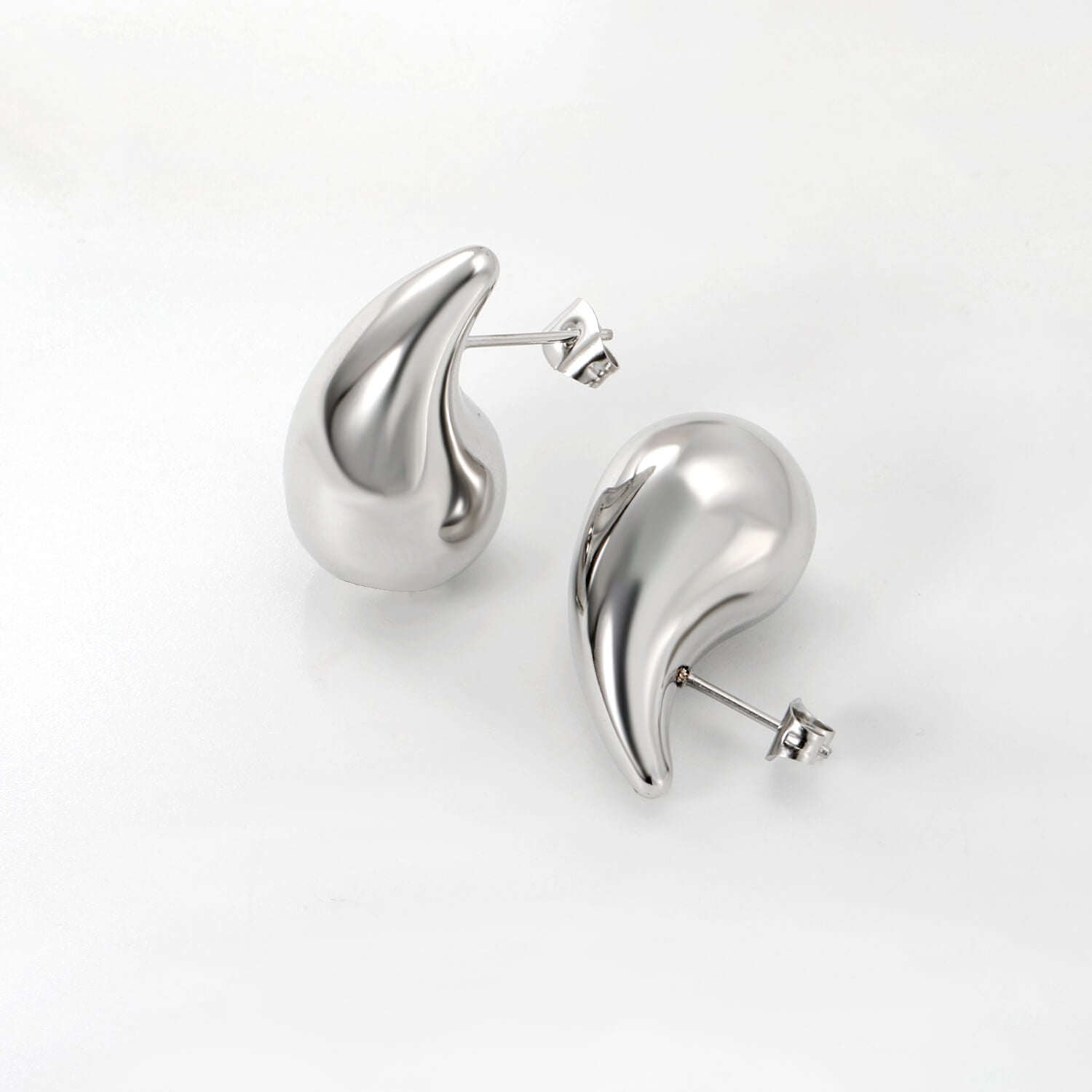 Pisaranmuotoiset madoww brändin ruostumattomasta teräksestä valmistetut hopean väriset korvakorut valkoisella taustalla