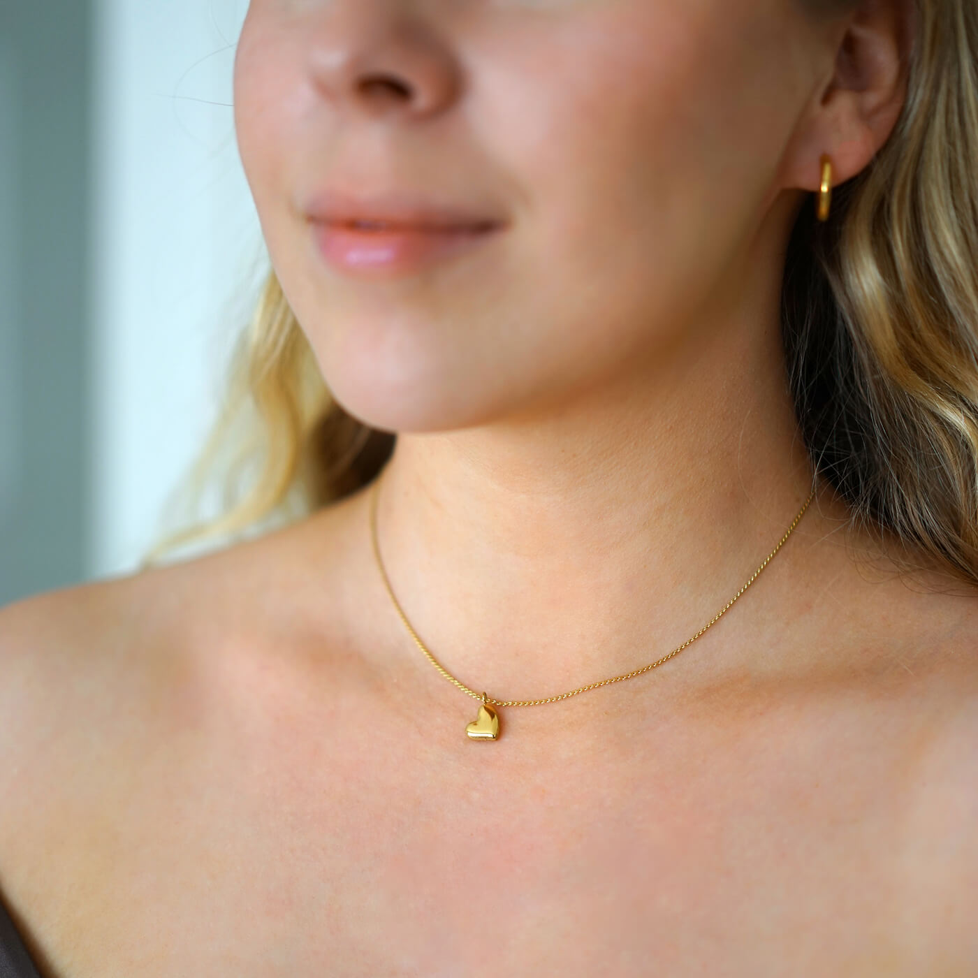 Kullattu sydänkaulakoru nuoren naisen kaulassa, joka on hypoallerginen