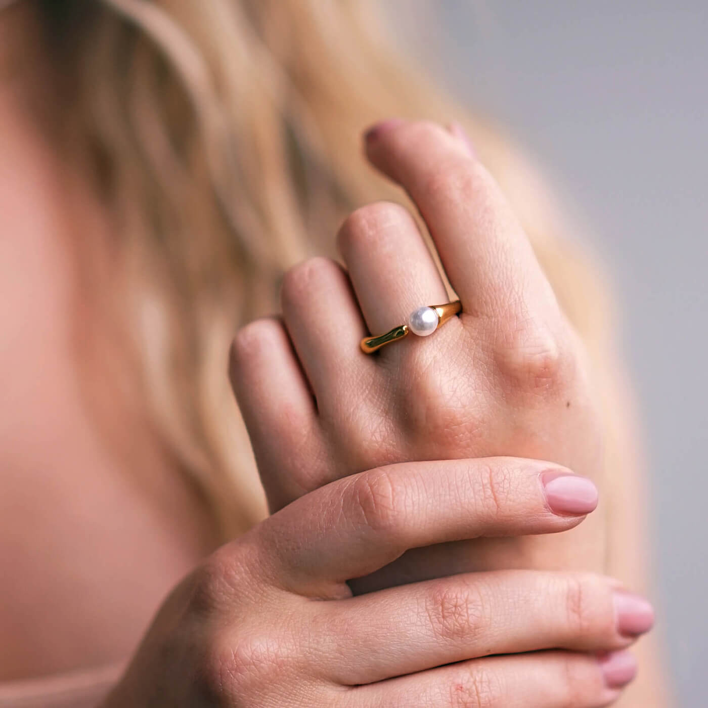 Kullattu helmisormus naisen kädessä