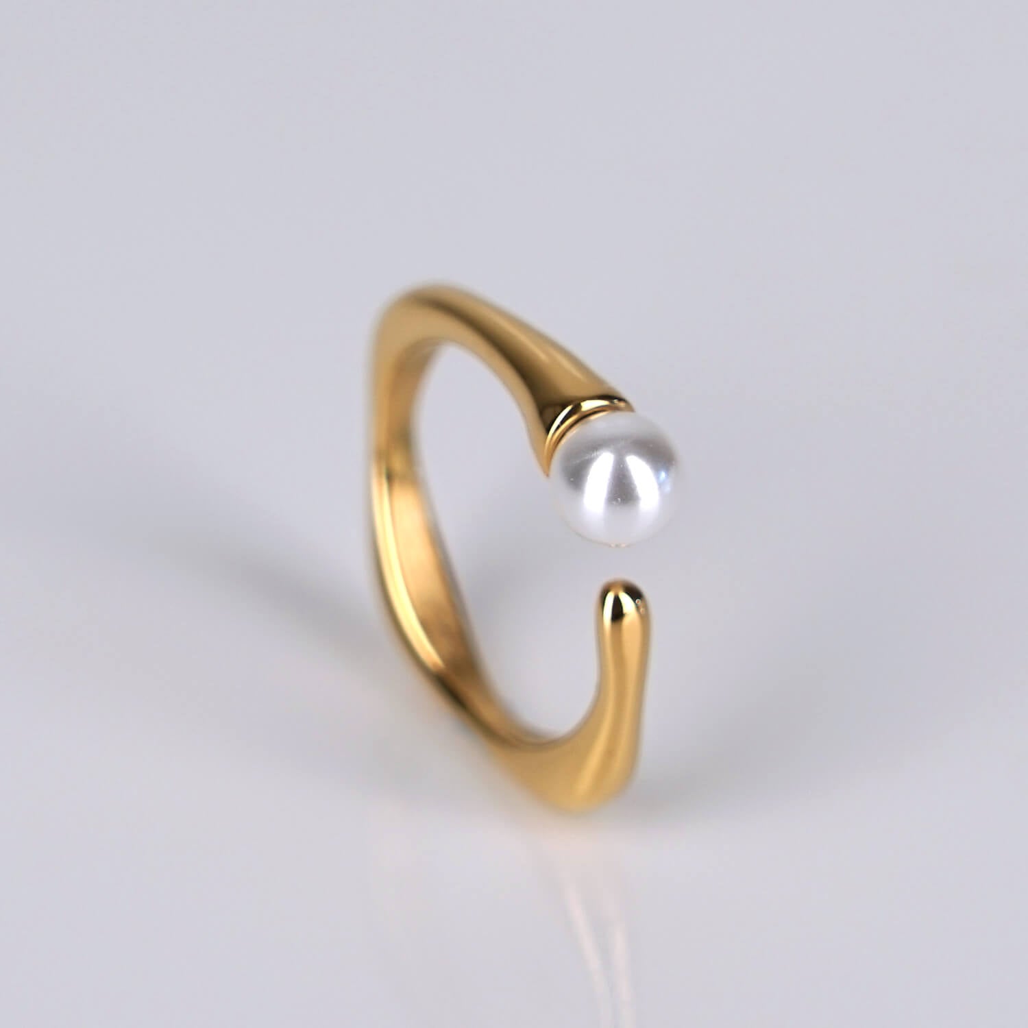 lähikuva kullatusta sormuksesta, jossa yksittäinen helmi