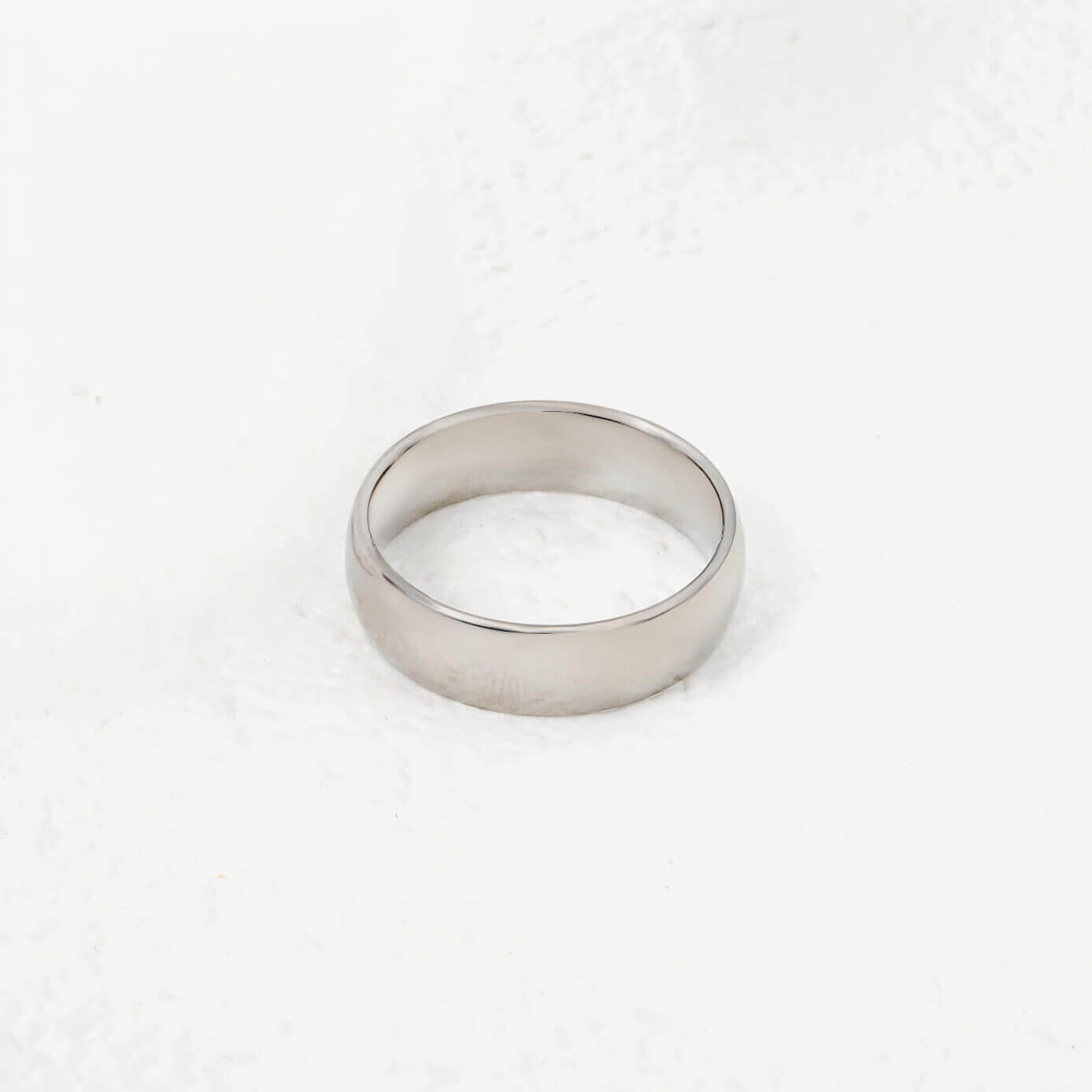 Hopean värinen teräs sormus valkoisella taustalla. Ihoystävällinen materiaali.