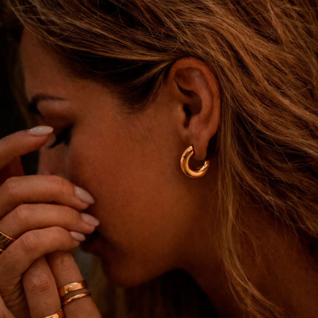 Nuori kaunis nainen jolla yllään madowwn kullatut chunky korvakorut