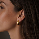 Dew Earring in gold worn on model, close-up side profile against a dark background.