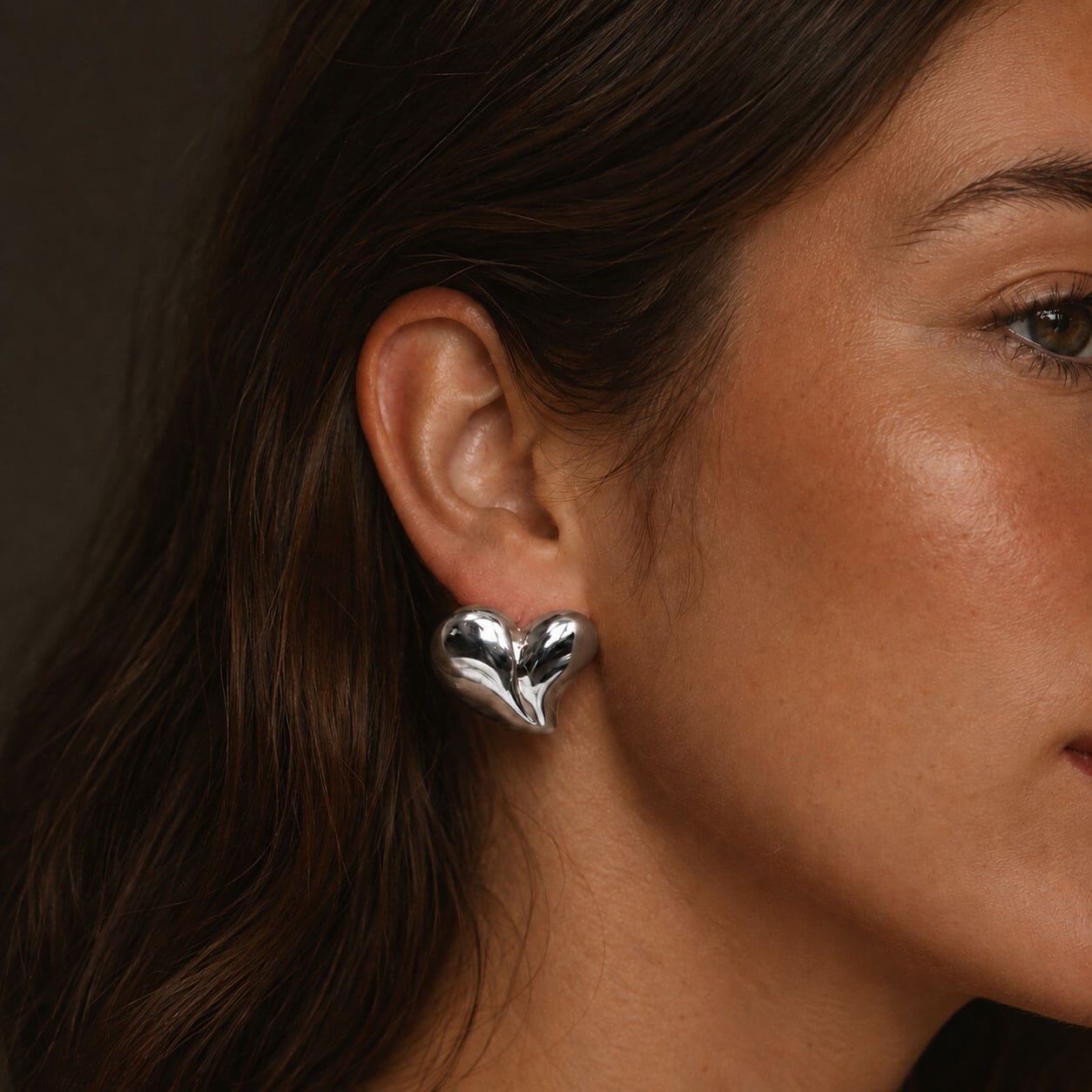 Heart earring, silver-tone heart-shaped stainless steel earring shown in a side-profile close-up.